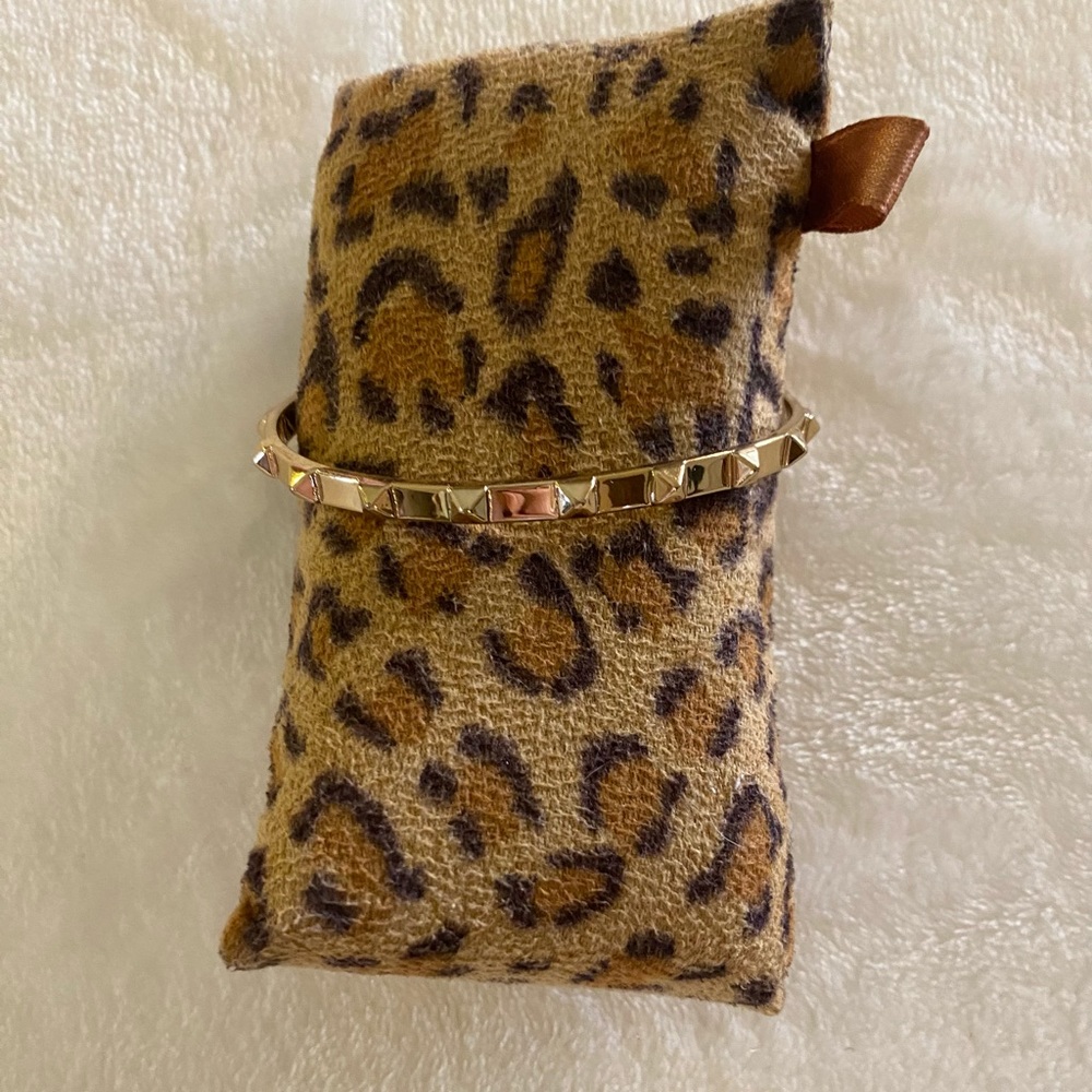 BCBGENERATION gold tone open bangle with chain.